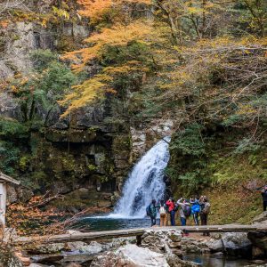 千手滝の紅葉を石橋から眺める人々