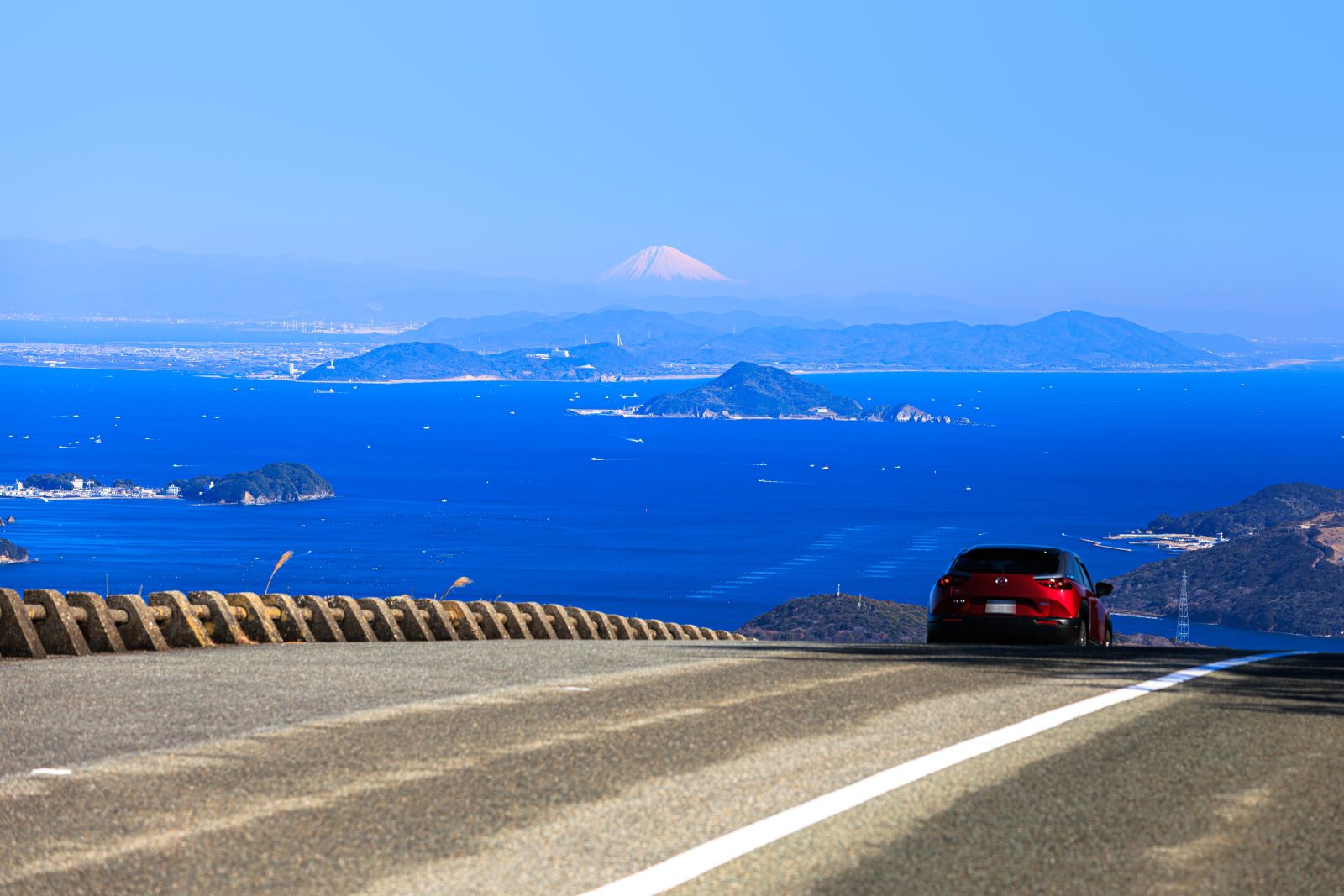 無料壁紙 鳥羽側の道路を走る車と絶景の富士山。PCとデスクトップ壁紙に最適な4K高画質の無料壁紙。三重県伊勢市の伊勢志摩スカイラインで撮影したフリー写真素材
