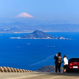 無料壁紙 鳥羽側の道路脇から富士山を眺める人。PCとデスクトップ壁紙に最適な4K高画質の無料壁紙。三重県伊勢市の伊勢志摩スカイラインで撮影したフリー写真素材
