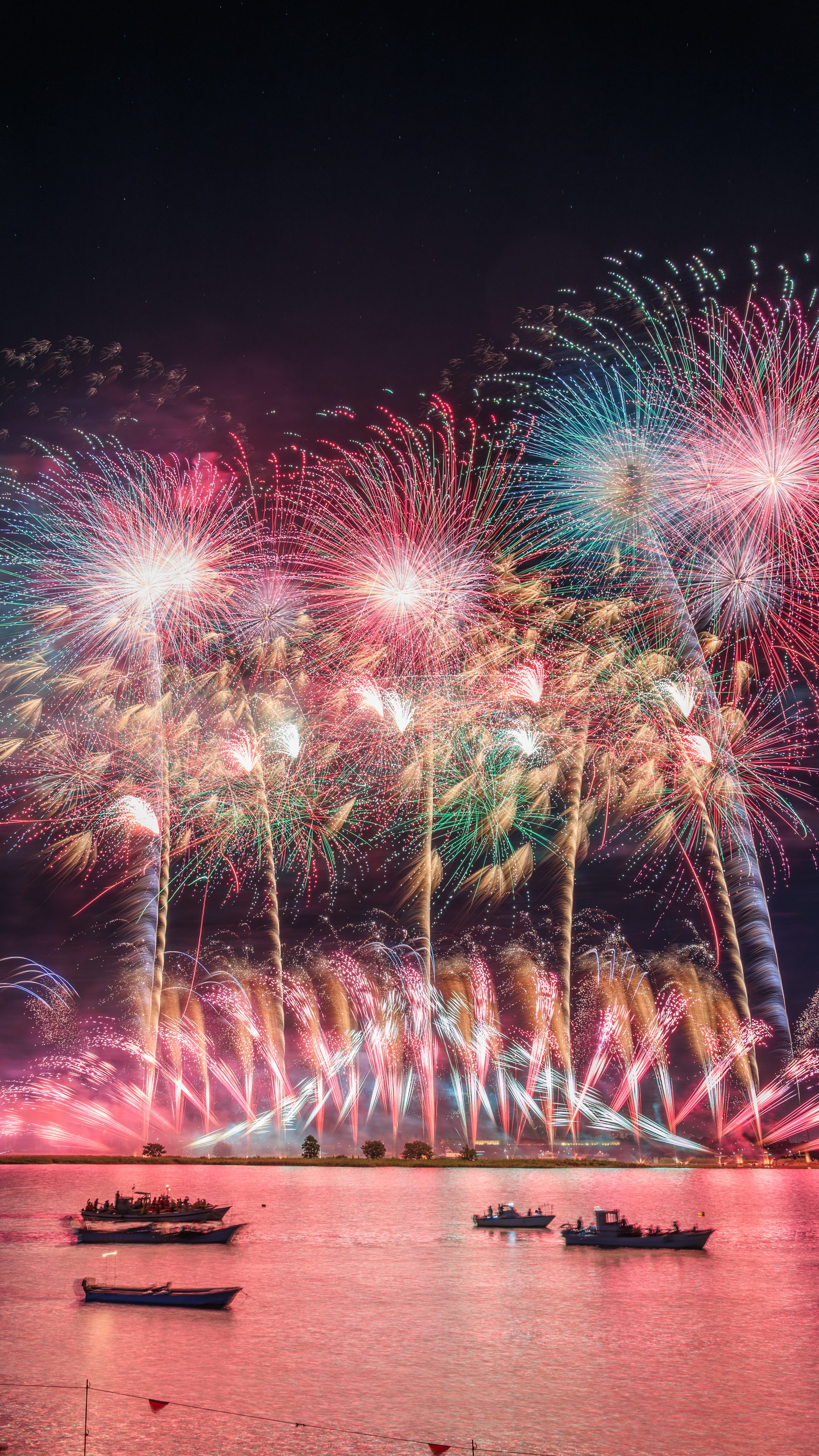 無料スマホ壁紙 ピンクに染まる夜空と揖斐川の花火。AndroidとiPhoneに対応した4K高画質の無料待ち受け画像。三重県桑名市の桑名水郷花火大会で撮影したフリー写真素材
