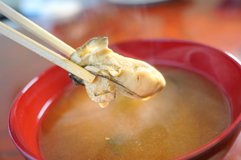 鳥羽浦村の牡蠣の写真「牡蠣の味噌汁から牡蠣の身を箸でつかむ」