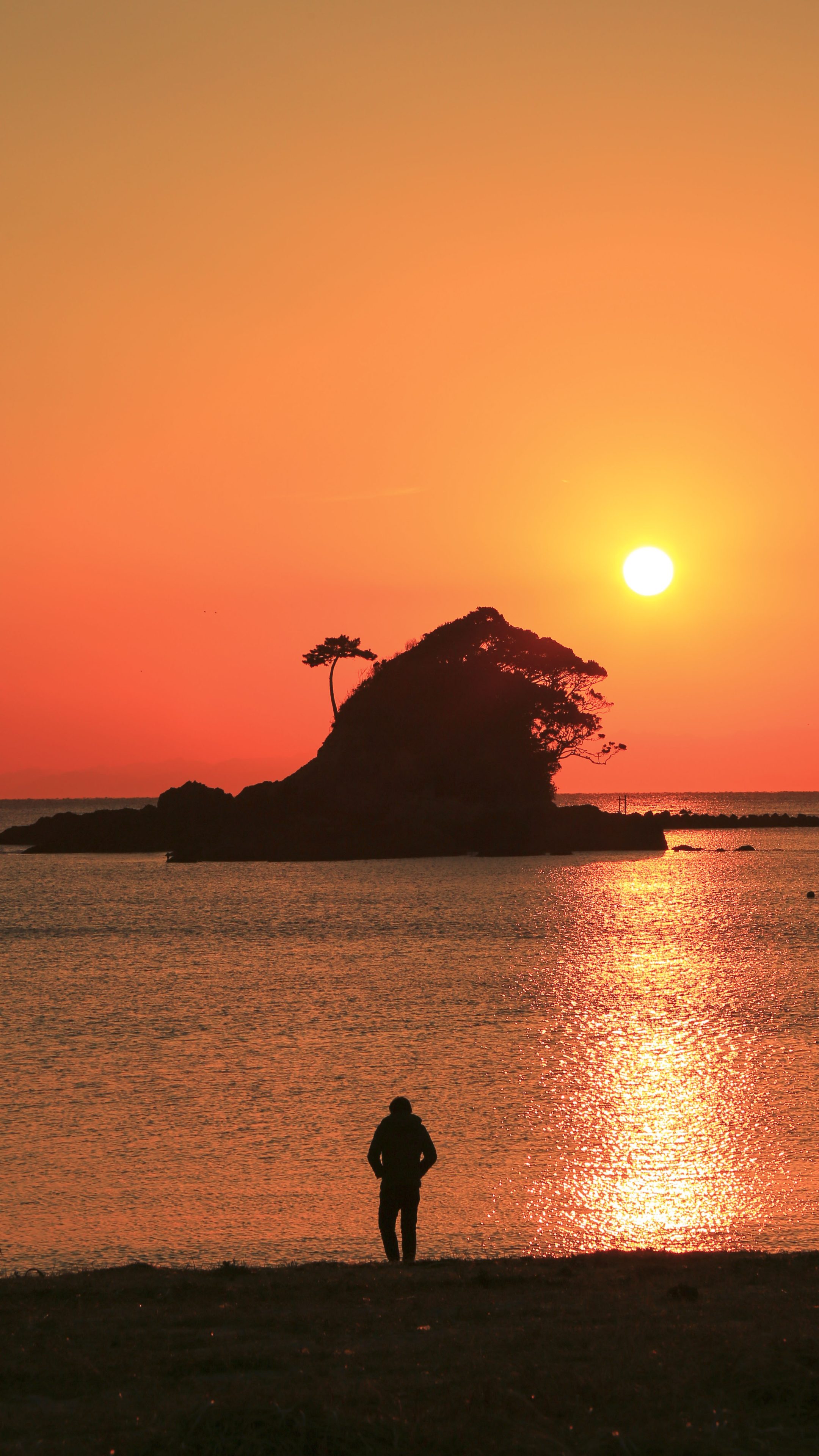 無料スマホ壁紙 ゴジラと夕陽を眺める人。AndroidとiPhoneに対応した4K高画質の無料待ち受け画像。三重県志摩市のあづり浜で撮影したフリー写真素材