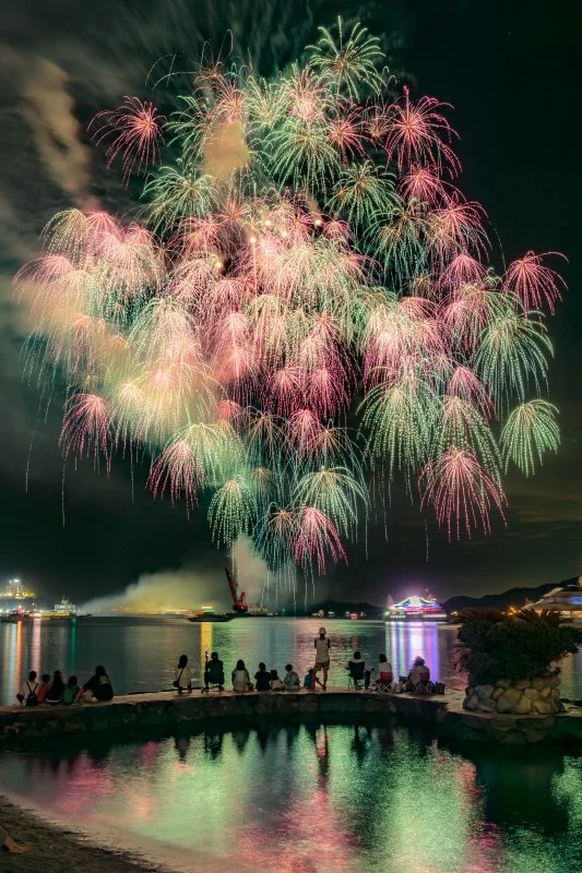 無料スマホ壁紙 青とピンクの彩色千輪菊と水面に映る花火。AndroidとiPhoneに対応した4K高画質の無料待ち受け画像。三重県鳥羽市の鳥羽みなとまつりで撮影したフリー写真素材