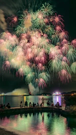 無料スマホ壁紙 青とピンクの彩色千輪菊と水面に映る花火。AndroidとiPhoneに対応した4K高画質の無料待ち受け画像。三重県鳥羽市の鳥羽みなとまつりで撮影したフリー写真素材