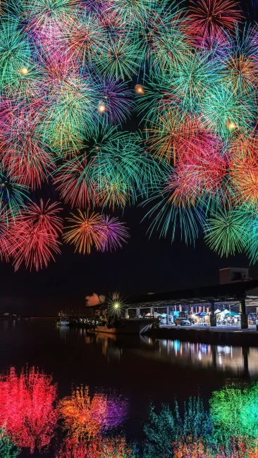漁港でアーチを描く虹色の花火（三重県尾鷲市・おわせ港まつり）