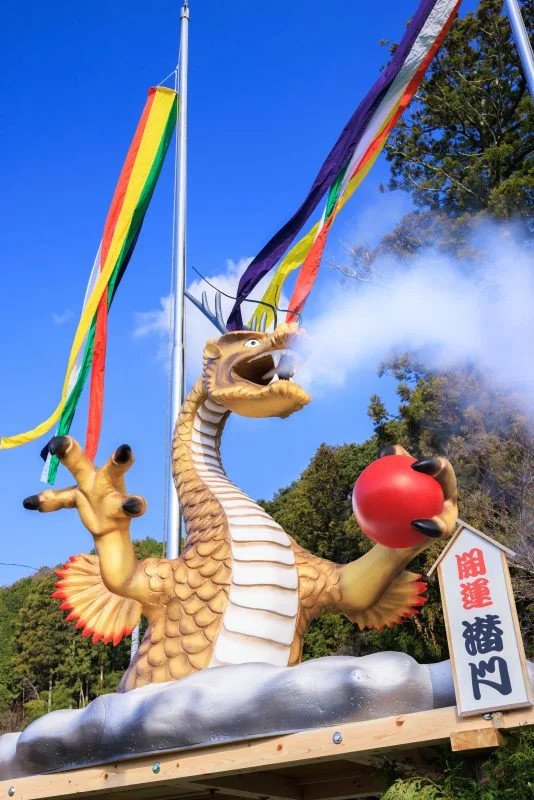 無料スマホ壁紙 青空の下で煙を噴き出す辰のジャンボ干支。AndroidとiPhoneに対応した4K高画質の無料待ち受け画像。三重県津市の辰水神社のジャンボ干支で撮影したフリー写真素材