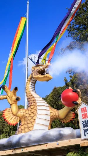 無料スマホ壁紙 青空の下で煙を噴き出す辰のジャンボ干支。AndroidとiPhoneに対応した4K高画質の無料待ち受け画像。三重県津市の辰水神社のジャンボ干支で撮影したフリー写真素材