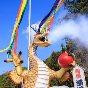 無料スマホ壁紙 青空の下で煙を噴き出す辰のジャンボ干支。AndroidとiPhoneに対応した4K高画質の無料待ち受け画像。三重県津市の辰水神社のジャンボ干支で撮影したフリー写真素材