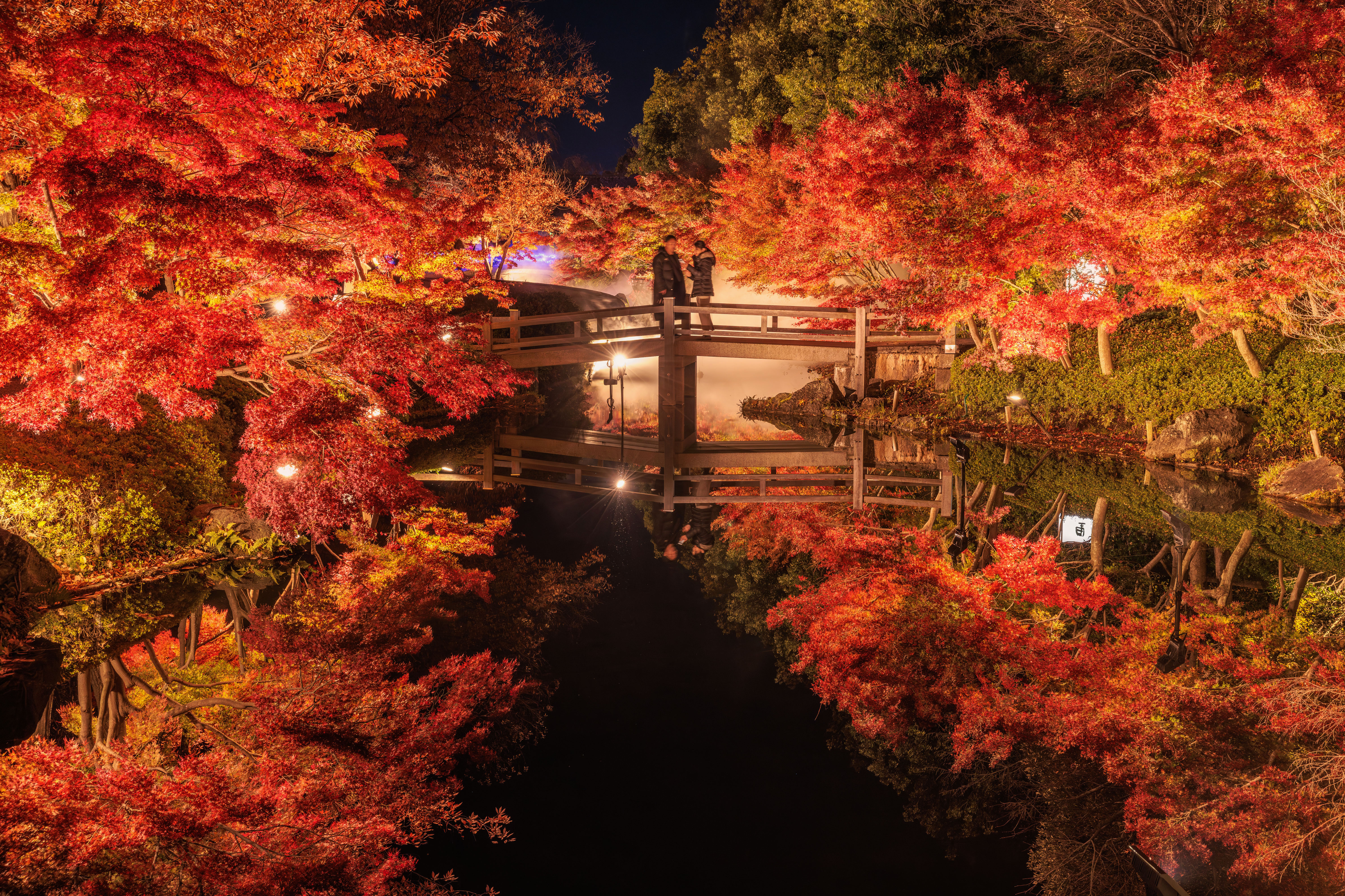 無料壁紙 鏡池の紅葉ライトアップを橋から眺める人。PCとデスクトップ壁紙に最適な4K高画質の無料壁紙。三重県桑名市のなばなの里で撮影したフリー写真素材