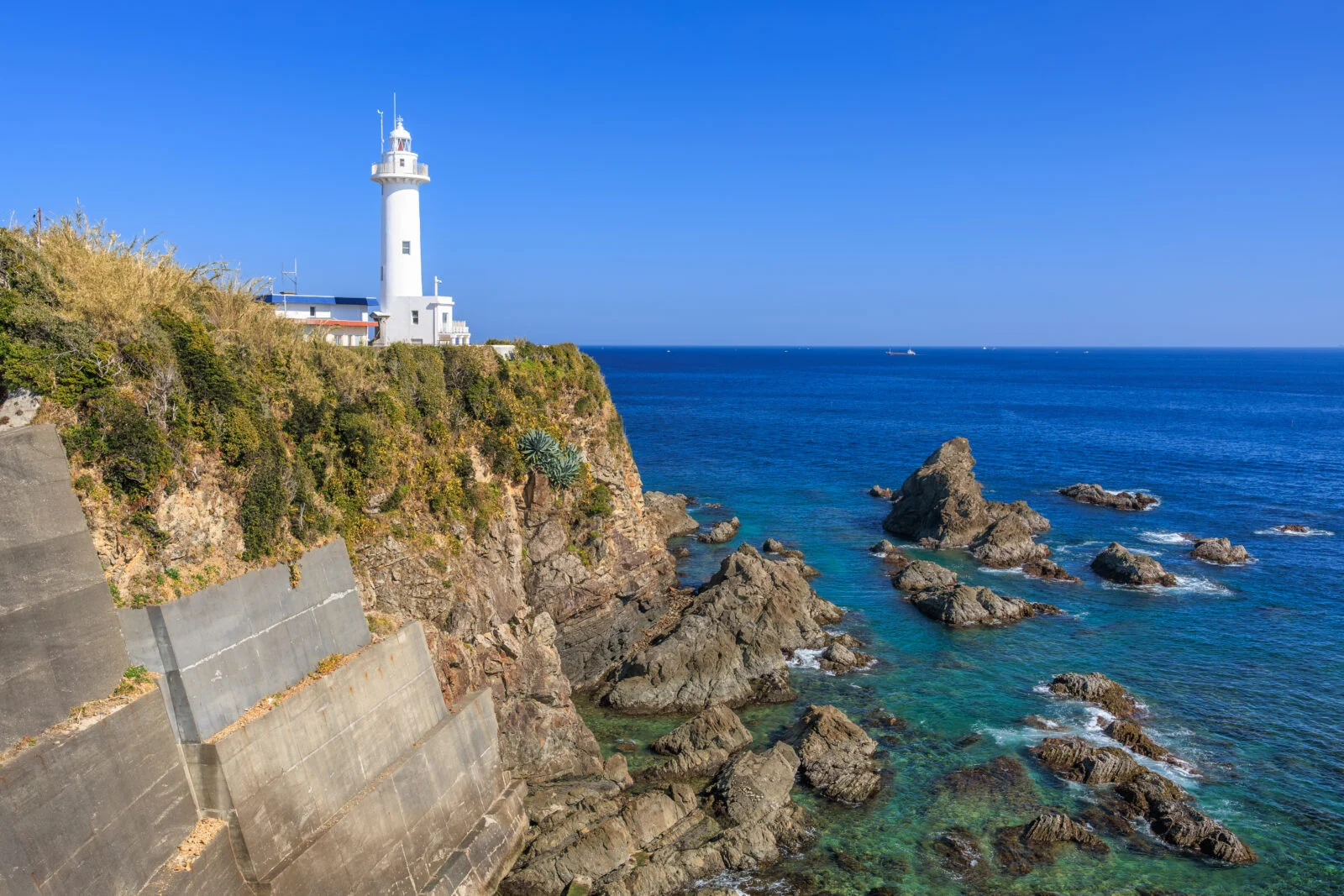 無料壁紙 青い海と澄んだ海の崖に建つ灯台。PCとデスクトップ壁紙に最適な4K高画質の無料壁紙。三重県志摩市の大王埼灯台で撮影したフリー写真素材