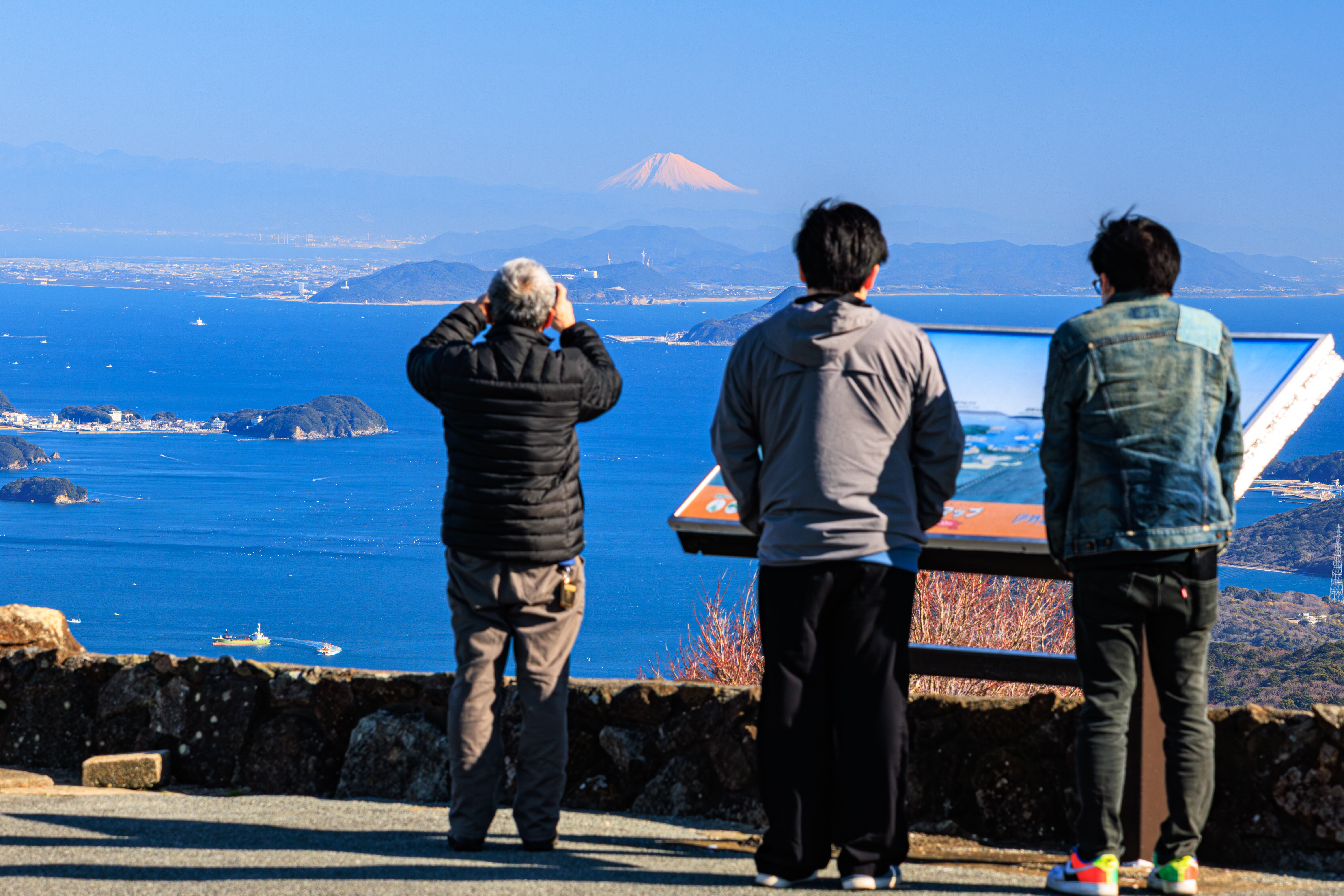 朝熊山頂の看板付近で富士山を見る人々(三重県伊勢市・伊勢志摩スカイライン)