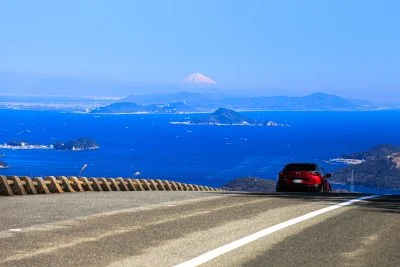 無料壁紙 鳥羽側の道路を走る車と絶景の富士山。PCとデスクトップ壁紙に最適な4K高画質の無料壁紙。三重県伊勢市の伊勢志摩スカイラインで撮影したフリー写真素材