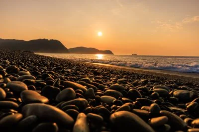 無料壁紙 みはま小石に降り注ぐ朝日。PCとデスクトップ壁紙に最適な4K高画質の無料壁紙。三重県熊野市の七里御浜で撮影したフリー写真素材